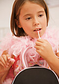 Girl wearing a pink feather boa and applying lip gloss