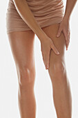 Frau, die Körperlotion auf die Beine aufträgt, tiefer Ausschnitt