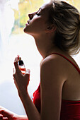 Junge Frau sprüht Parfüm auf den Hals