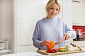 Lächelnde Frau beim Zubereiten von Gemüse