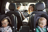 Familie mit Babyzwillingen im Auto sitzend