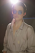 Junge Frau im Trenchcoat und mit blau getönter Sonnenbrille