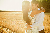 Lächelndes Paar umarmt sich in einem Feld