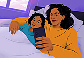 Happy, affectionate mother and son cuddling in bed, taking selfie with smart phone