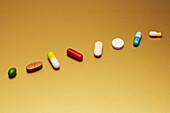 Still life arrangement variety of medication pills and capsules on yellow background