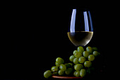 Glas mit Weißwein und Weintrauben