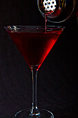 Einschenken eines Cocktails in ein Martini-Glas