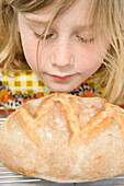 Junges Mädchen riecht an einem Laib Brot