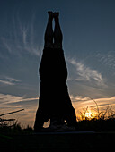 Man Practicing Yoga Outdoors at Sunset, Headstand pose