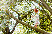 Frau in geblümtem Kleid tanzend auf Baumstamm im Wald