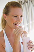 Frau trinkt einen Joghurt-Smoothie mit einem Strohhalm