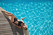 Elevated view of a woman sunbathing on the edge of a swimming pool