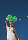 Frau hält lächelnd ein Bündel grüner Luftballons - Tiefblick