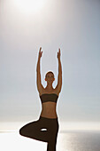 Junge Frau übt Yoga mit dem Meer im Hintergrund