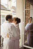 Couple kissing in front of an open window