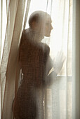Silhouette einer Frau hinter einem halbtransparenten Vorhang, Profil