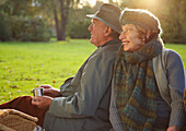 Älteres Paar sitzt nebeneinander in einem Park