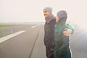 Lächelndes Paar auf der Landebahn eines Flughafens stehend