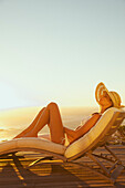 Frau beim Sonnenbaden auf einem Liegestuhl bei Sonnenuntergang