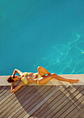 Woman Sunbathing by Swimming Pool, High Angle View