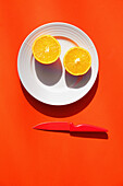 Halbierte Orange auf Teller mit Messer