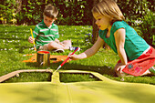Junge und Mädchen bemalen Pappausschnitte im Garten