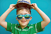 Lächelnder Junge mit Strohhut und Sonnenbrille