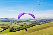 Gleitschirmflieger am Mount Caburn, die über der Grafschaftsstadt Lewes, East Sussex, England, Vereinigtes Königreich, Europa fliegen