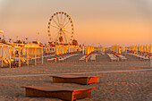 Blick auf Riesenrad und Sonnenschirme auf dem Lido am Strand von Rimini bei Sonnenaufgang, Rimini, Emilia-Romagna, Italien, Europa