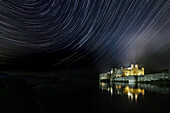 Beleuchtetes Schloss Leeds, das sich im Wassergraben spiegelt und Sternenspuren am Nachthimmel zeigt, bei Maidstone, Kent, England, Vereinigtes Königreich, Europa