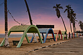 Blaue Stunde über dem Strand mit kolonialen Betonstrandschirmen in der Stadt Namibe, Angola, Afrika
