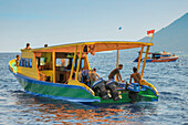 Dive boat with young foreign tourists and crew off coral fringed holiday and scuba island, Bunaken, North Sulawesi, Indonesia, Southeast Asia, Asia