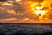 Blick bei Sonnenuntergang von der Insel Walney über die Irische See auf den entfernten Offshore-Windpark Walney, Küste von Cumbria, Cumbria, England, Vereinigtes Königreich, Europa