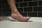 Nackter Fuß einer nicht identifizierten Person in einer Dusche
