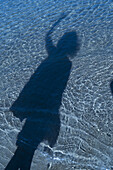 Schatten einer nicht identifizierten Person auf blauem Wasser
