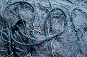 Ein Haufen verwahrloster Fischernetze und Seile liegen auf einem Pier herum