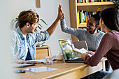 Two coworkers high fiving during meeting in office