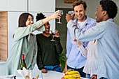 Gruppe von Freunden stößt mit Weingläsern an, während sie in einem Haus abhängen