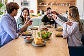 Gruppe von Freunden stößt während eines Abendessens mit Weingläsern an