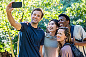 Young adult man taking a selfie with friends during hiking excursion