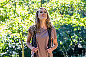 Beautiful woman wearing backpack while hiking in the woods