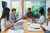 Business people discussing project while gathered at office