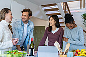 Group of friends drinking wine while hanging on kitchen