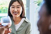 Young adult woman smiling while talking with friend while drinking wine