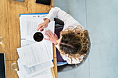 Advertising agency worker drinking coffee while doing paper work