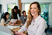 Financial assistant using smart phone while looking and laughing at the camera