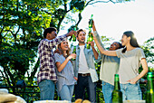 Fünf Freunde erheben Bierflaschen und stoßen auf einer Dachterrassenparty an
