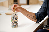 Beschnittene Ansicht einer Männerhand, die Batterien aus einem Glasgefäß entfernt