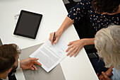 Erwachsene Frau, die während eines Gesprächs mit einem Anwalt einen Vertrag unterschreibt
