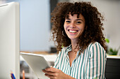 Young adult businesswoman looking at the camera while using digital tablet